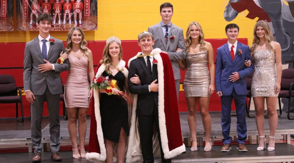 Un gruppo di persone vestite a festa posa davanti a decorazioni cinesi alla Kuemper Catholic High School.