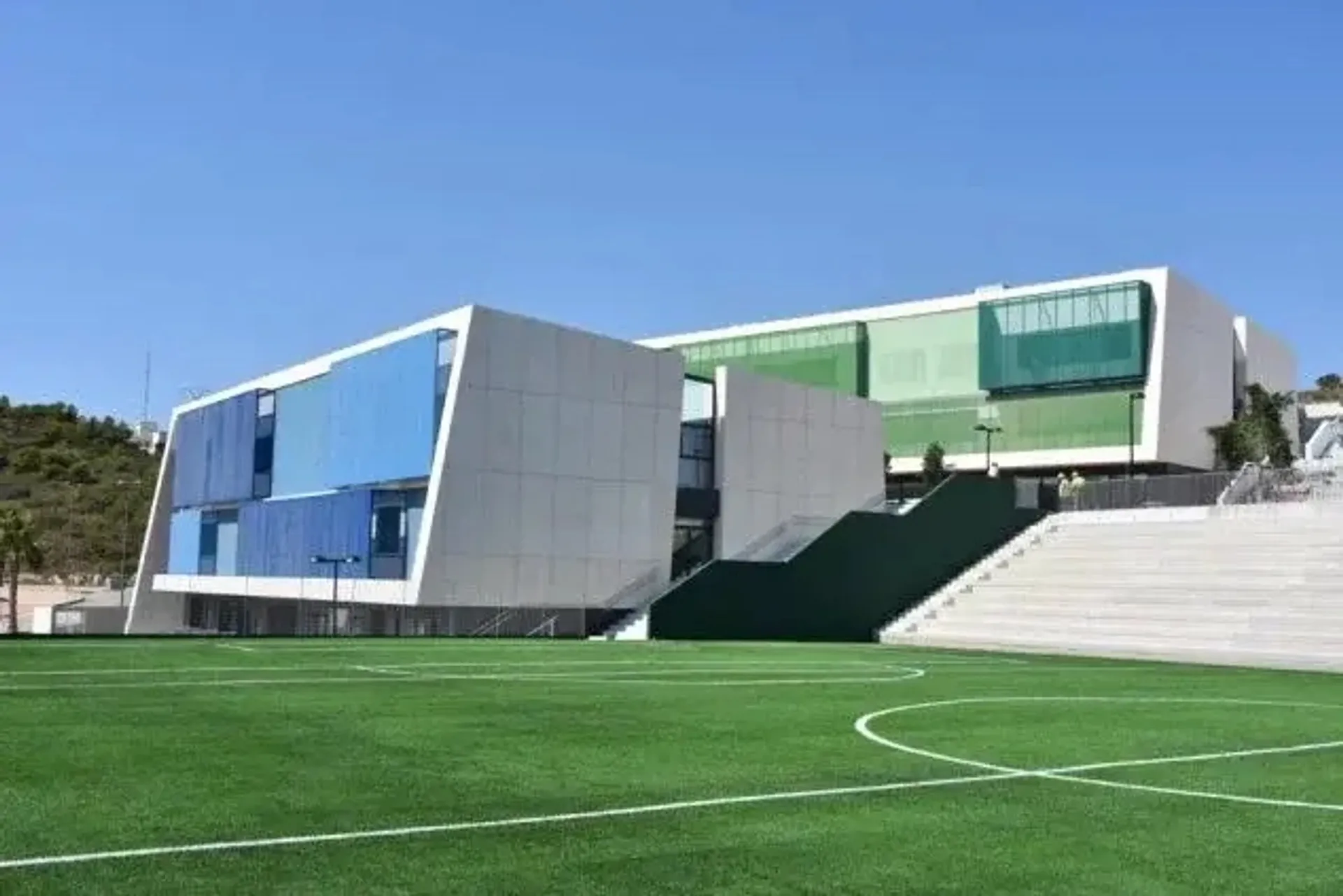 L'edificio moderno e multicolore della Laude Lady Elizabeth School con un campo in erba sintetica verde in primo piano sotto un cielo blu.