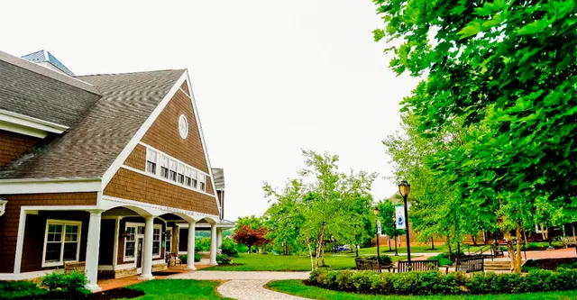Un affascinante edificio in legno con veranda coperta nel campus della Garrison Forest School circondato da un paesaggio ben curato.