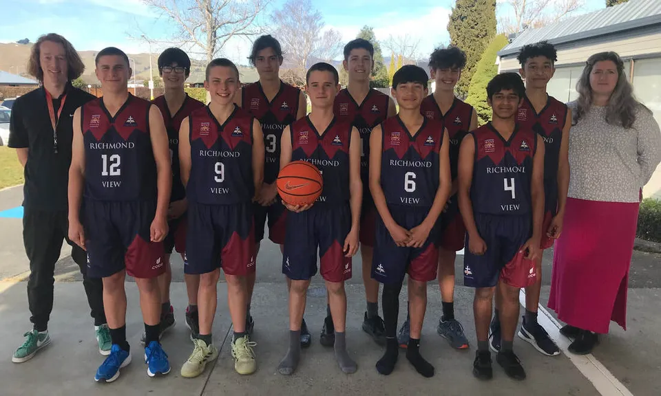 La squadra di pallacanestro della Richmond View School posa all'aperto insieme ai suoi allenatori.