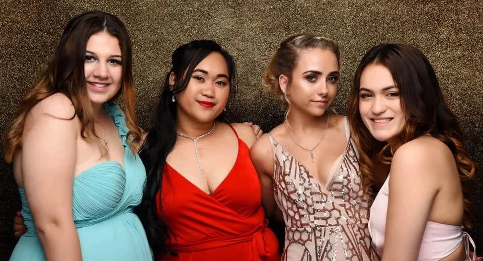 Quattro studentesse dell'Alfriston College posano insieme davanti a uno sfondo dorato.