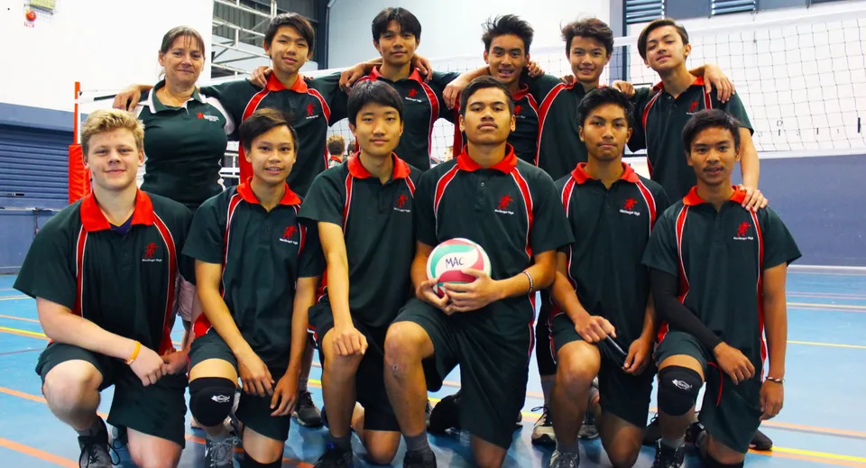 Un gruppo di giovani atleti in posa nell'impianto sportivo della MacGregor State High School con le loro tute sportive uniformi.