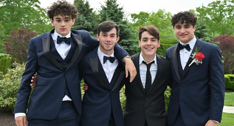 Un gruppo di giovani uomini in abito formale è insieme sul campus immerso nel verde del Cistercian College.