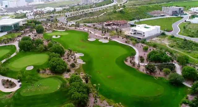 Il campo da golf della Bishop’s Gate Golf Academy si presenta con green e fairway ben curati sullo sfondo di un paesaggio urbano.