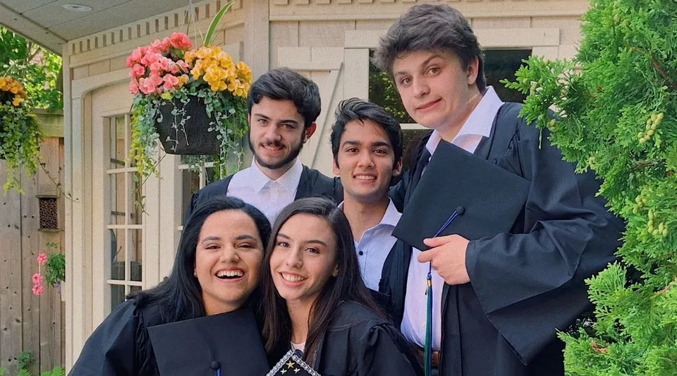Un gruppo di studentesse e studenti della Iroquois Ridge High School in abito formale in un giardino con fiori e spazi verdi.