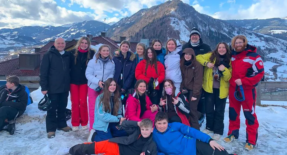 Un gruppo di studenti della Larkmead School posa davanti a un'impressionante scenografia di montagne innevate.