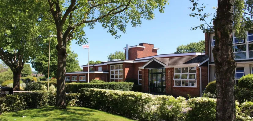 L'edificio in mattoni della Ringwood School con il tetto rosso sorge immerso nel verde, circondato da alberi e siepi curate.