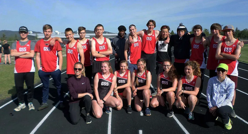 Un gruppo di giovani atleti della Golden Secondary School posa insieme sulla pista di atletica con le montagne sullo sfondo.