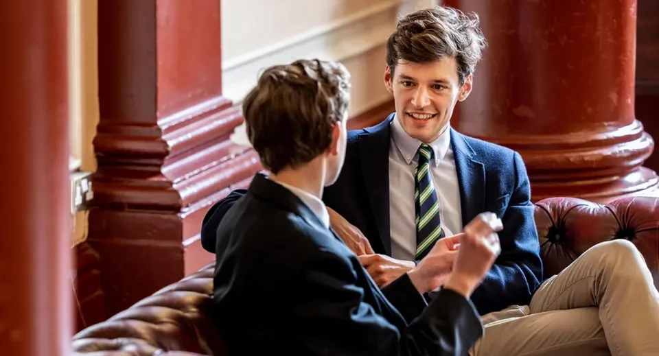 Due persone conversano in un ambiente formale all'interno del campus del Dulwich College.