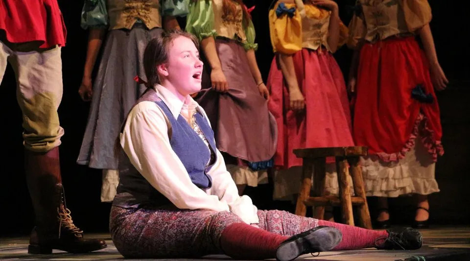 Una studentessa della Summerland Secondary School canta seduta sul palco durante una rappresentazione teatrale.