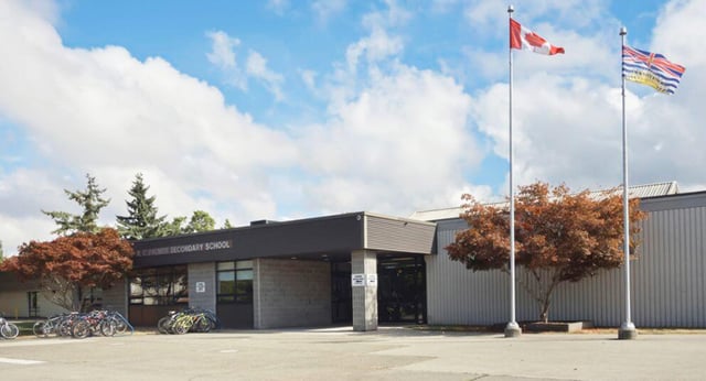 L'edificio moderno di colore nero della R.C. Palmer Secondary School è circondato da alberi e mostra diverse bandiere nazionali all'esterno.