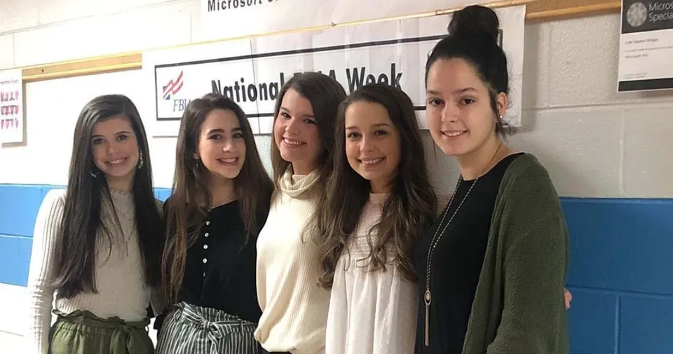 Cinque studentesse sono in piedi davanti a una parete con la scritta National Math Week nel campus della Pleasant Valley High School.