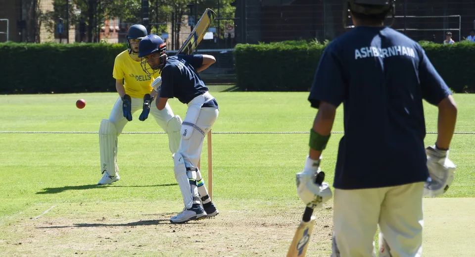 Gli studenti della Westminster School giocano a cricket su un campo in erba.