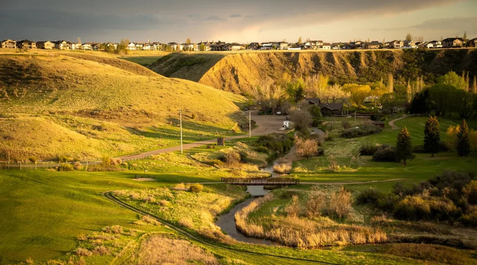 Un paesaggio verde con un sentiero tortuoso e un villaggio sullo sfondo vicino alla Monsignor McCoy High School.