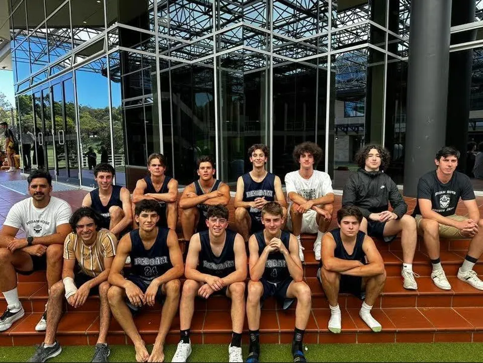 Un gruppo di studenti della Reddam House in abbigliamento sportivo siede sulle scale davanti a un edificio in vetro.