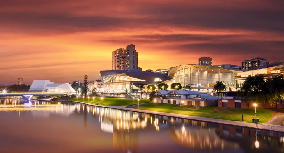Un lago calmo riflette i moderni grattacieli della città al tramonto, senza un riferimento diretto alla Pembroke School.
