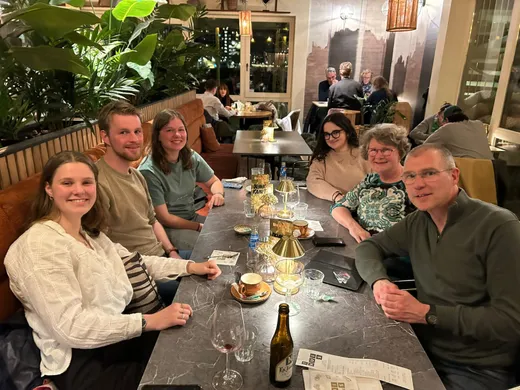 Gruppo di persone a cena a un tavolo di ristorante in un'atmosfera serale accogliente