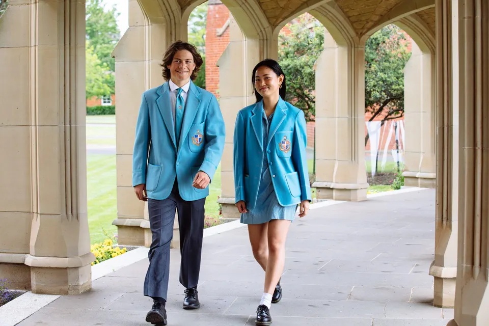 Due persone si trovano nel corridoio con finestre ad arco nel campus della Geelong Grammar School.