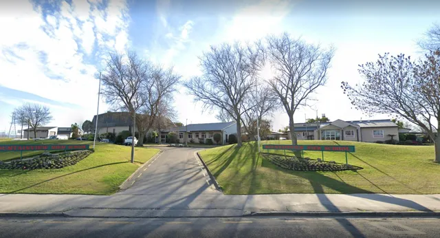 Un sentiero pavimentato attraversa un prato ben curato con alberi spogli nel campus della Mountainview High School.
