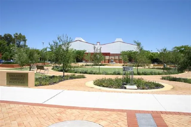 L'area esterna del Ballajura Community College mostra una fontana centrale circondata da un parco verde e un edificio caratteristico sullo sfondo.