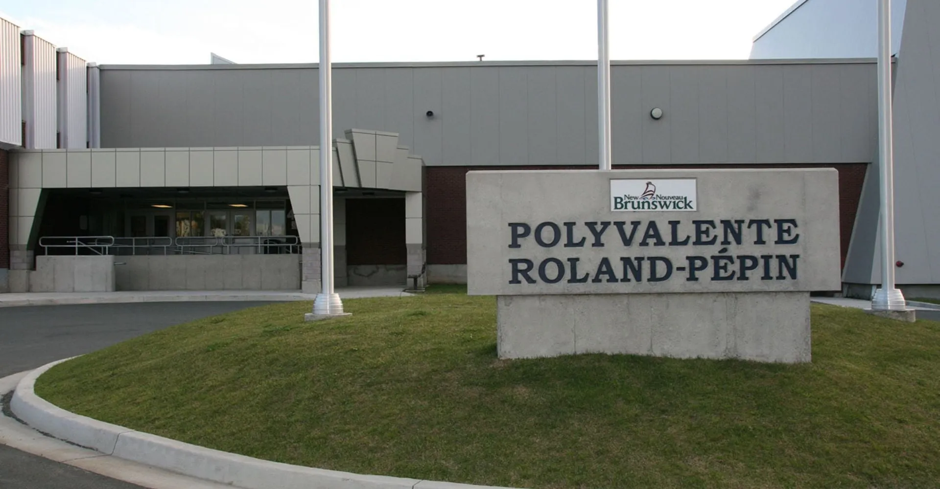 L'edificio moderno della Polyvalente Roland-Pépin con una grande insegna all'ingresso e un prato antistante.
