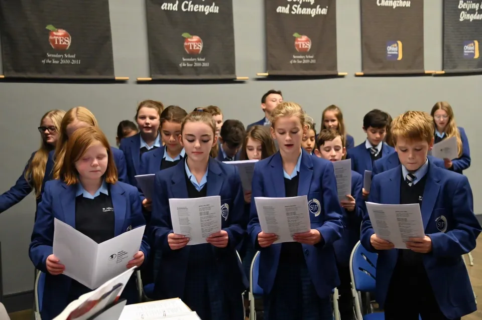 Studenti del St. John Plessington Catholic College in divisa scolastica sono davanti a scaffali con libri e materiali.