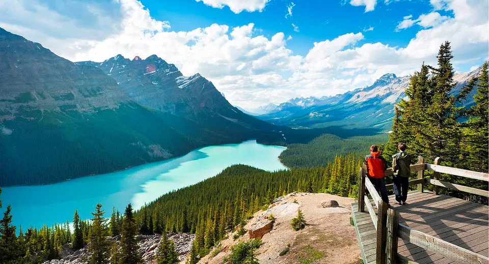 Una persona si trova su un pontile di legno e guarda il lago turchese davanti alle montagne nel terreno della Rutland Senior Secondary School.