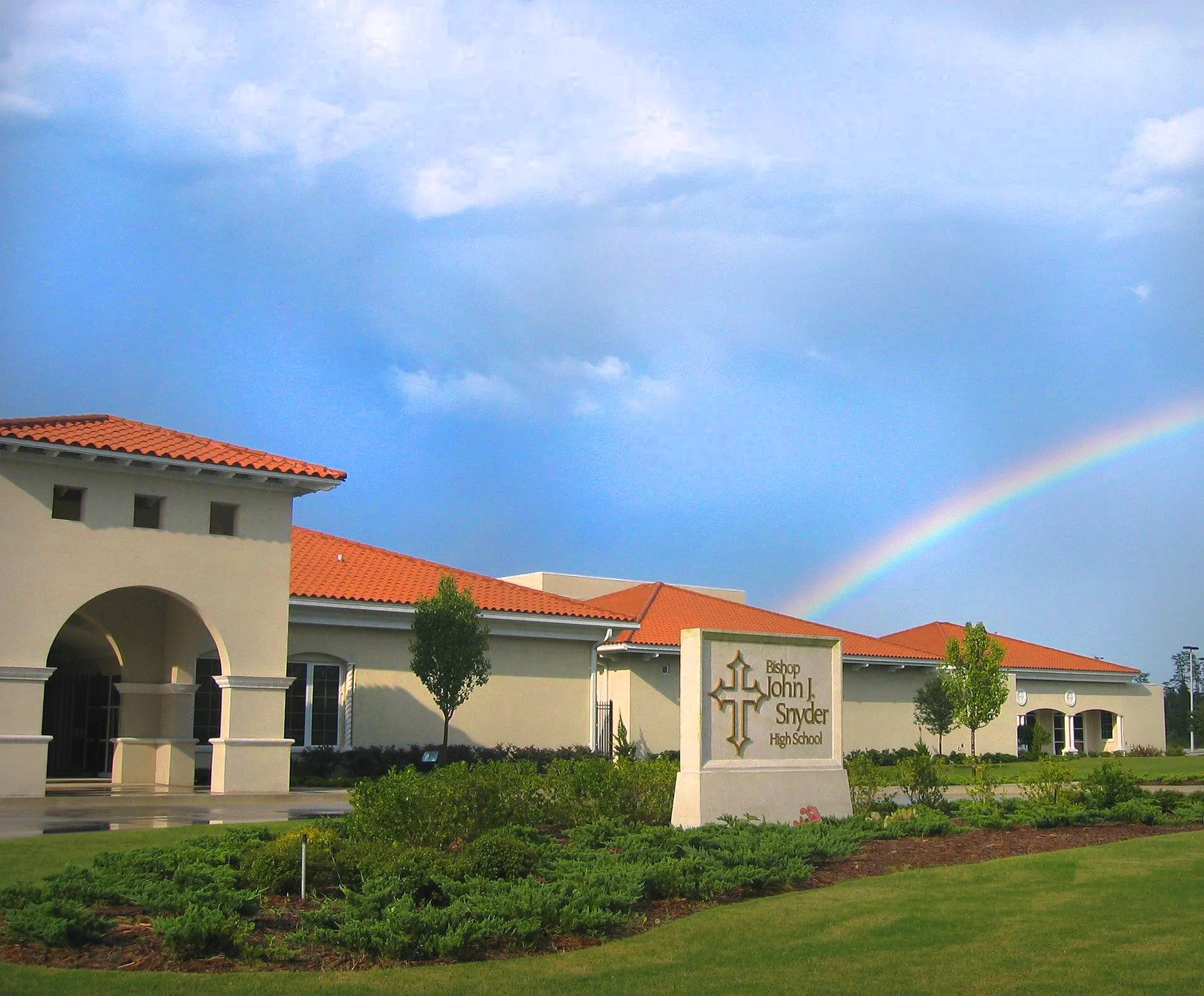 Un arcobaleno si stende sopra un edificio in stile mediterraneo con tetti in terracotta nel campus della Bishop J Snyder High School.