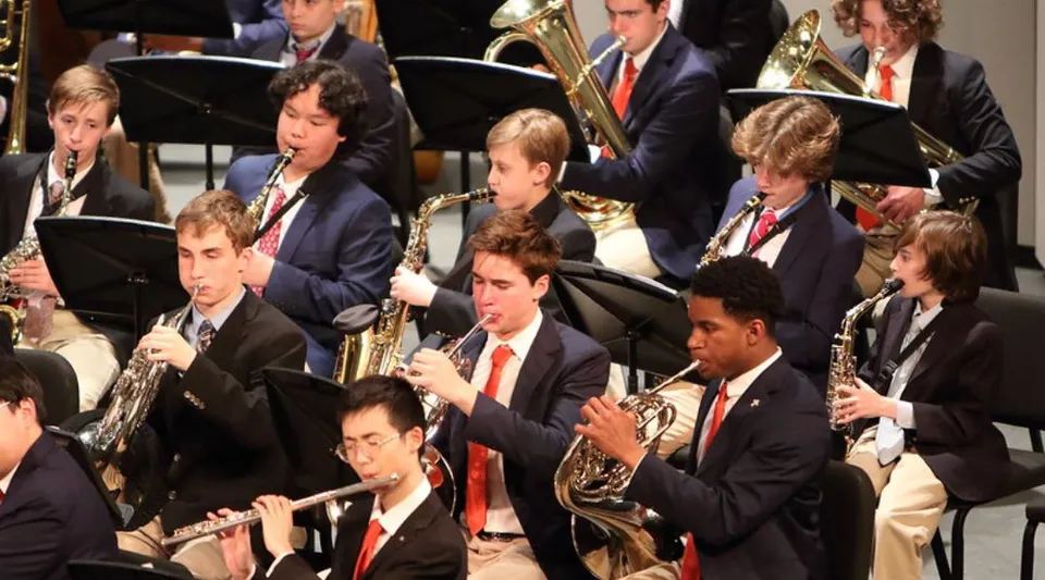 L'orchestra della Chaminade College Preparatory School suona in abito formale su un palco davanti a uno sfondo scuro.