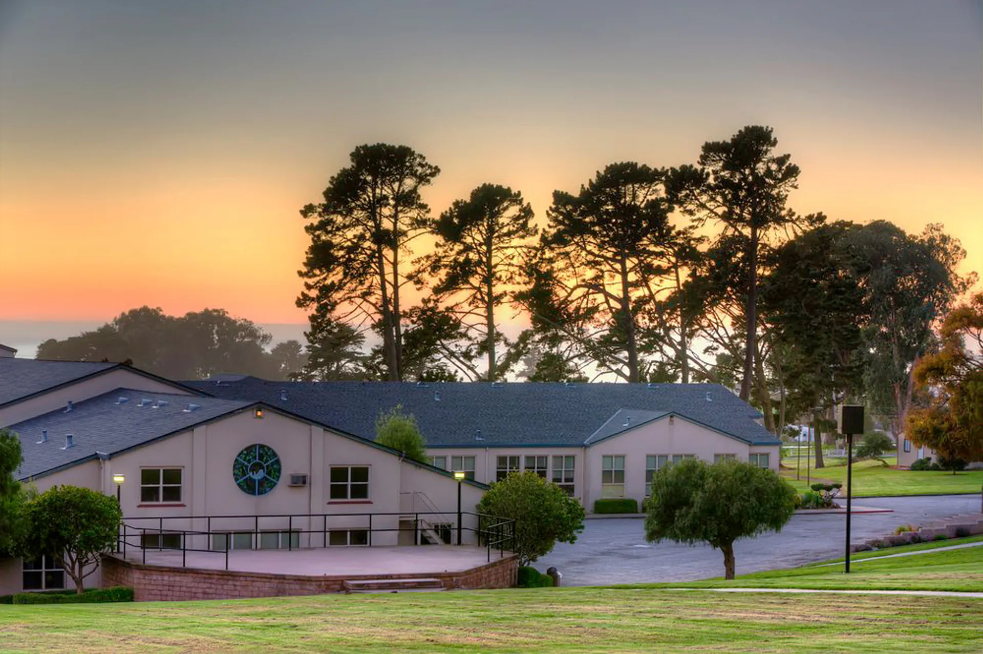 La zona residenziale con alti pini davanti al tramonto colorato nel campus della Monterey Bay Academy.