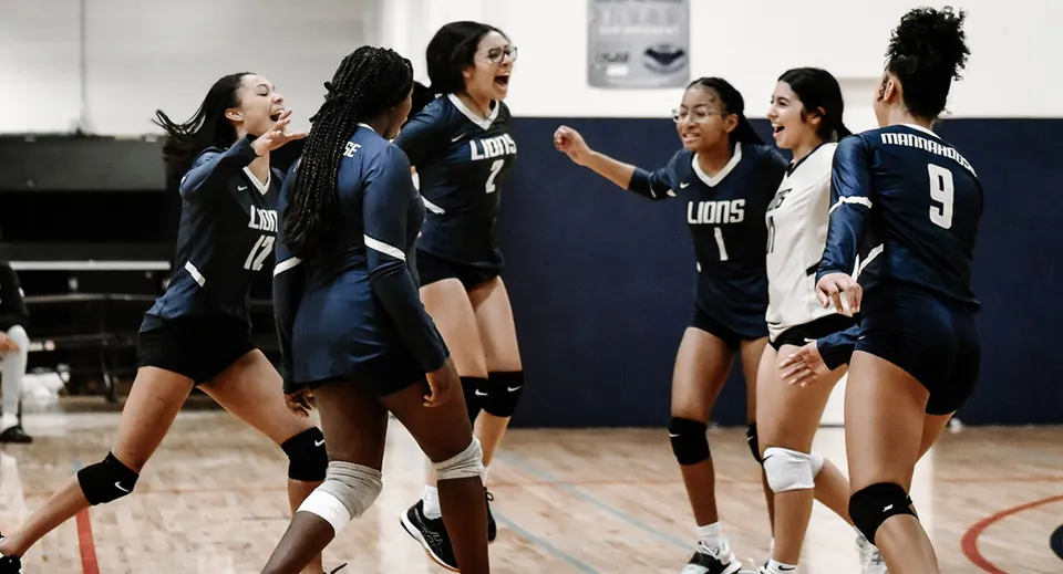 Giocatrici di pallavolo della Mannahouse Christian Academy festeggiano insieme sul campo da gioco.