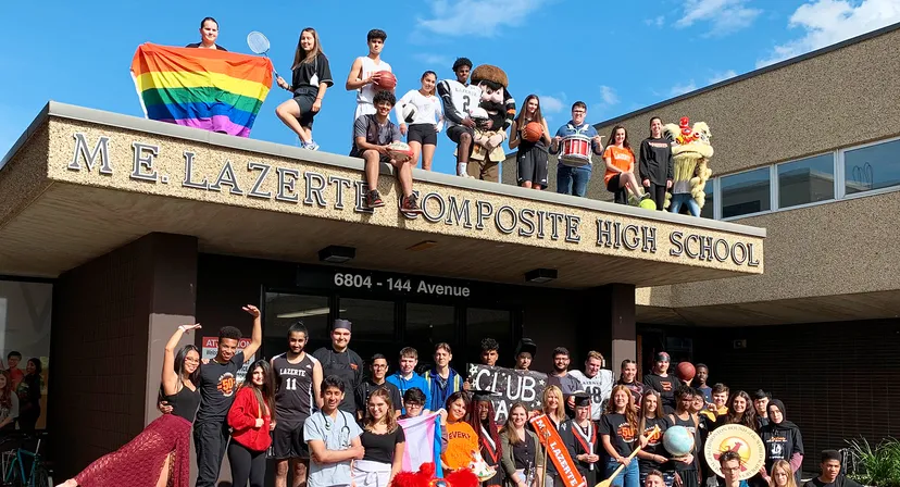 Studenti e membri dello staff della M.E. LaZerte Composite High School sono davanti all'edificio scolastico con una ben visibile bandiera arcobaleno.