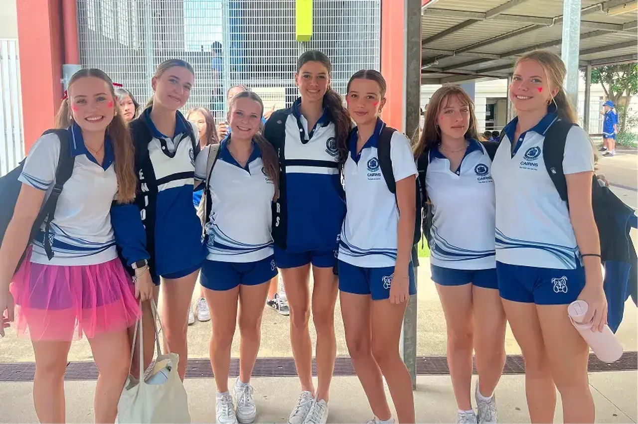 Gruppo di studentesse in divisa sportiva blu e bianca sorridono nel cortile della scuola in Australia
