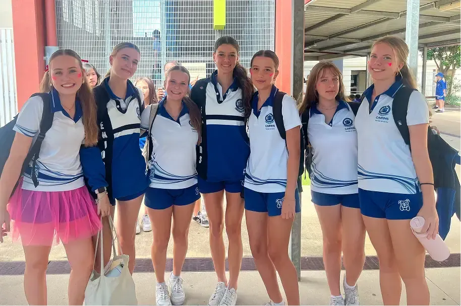 Gruppo di studentesse in divisa sportiva blu e bianca sorridono nel cortile della scuola in Australia
