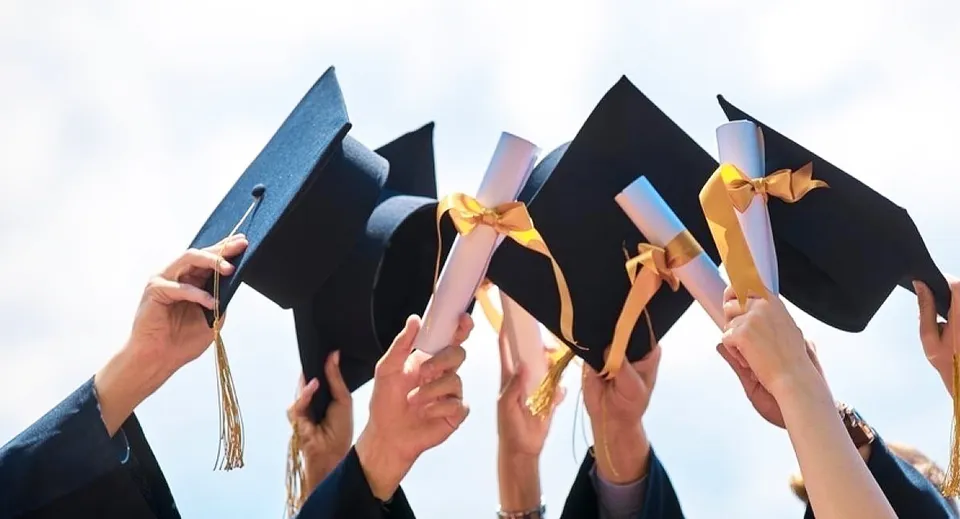 Studenti della Harry Ainlay High School tengono i loro tocchi da diploma in aria per festeggiare il diploma.