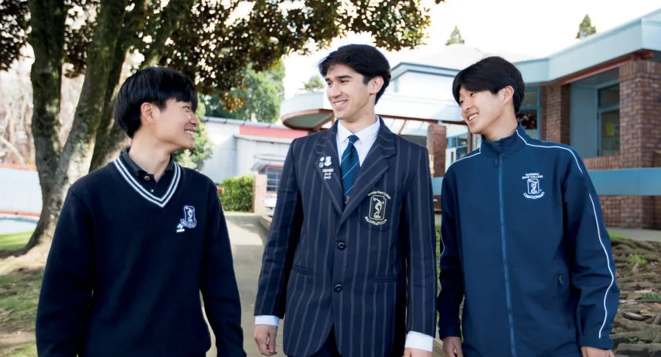 Tre studenti in divisa scolastica sono insieme nel cortile del Tauranga Boy's College.