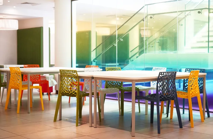Mensa di Parry e Garden Halls con tavoli bianchi, sedie colorate e ringhiera in vetro