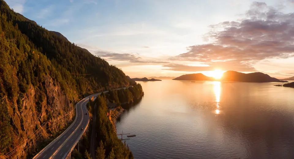 Una strada costiera si snoda lungo ripide scogliere con vista su acque calme al tramonto vicino alla St. Michaels University School.