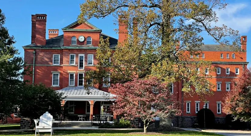 L'edificio storico in mattoni con una torre della Westtown School si erge circondato da alberi autunnali sotto un cielo blu.