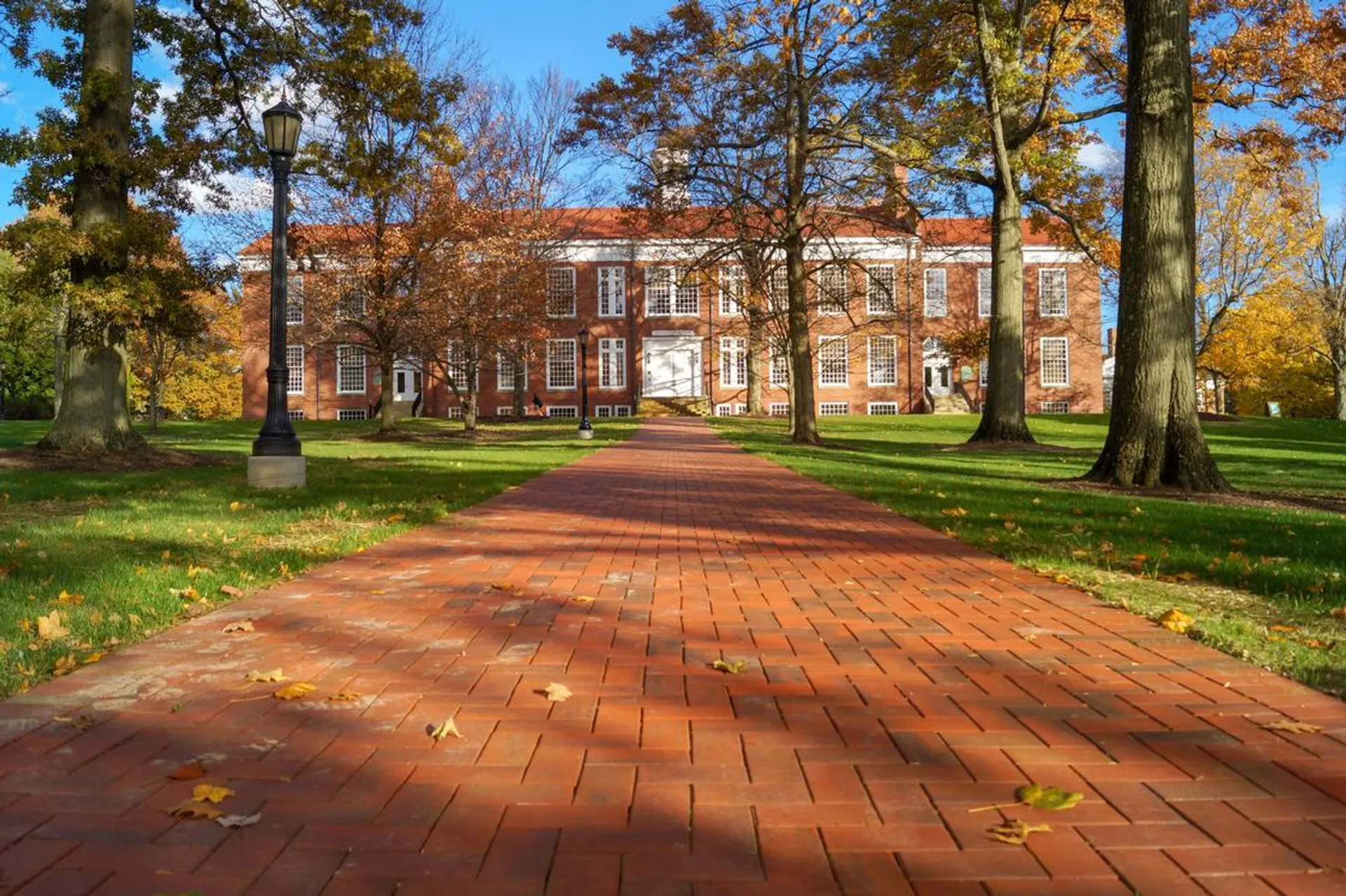 Un viale pavimentato attraversa il campus alberato della Western Reserve Academy, con un edificio in mattoni e i colori dell'autunno sullo sfondo.