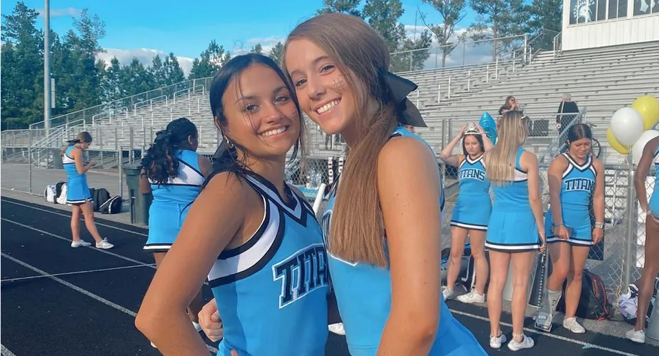 Due studentesse in divisa da cheerleader si abbracciano sul campo sportivo del Chesterfield School District.