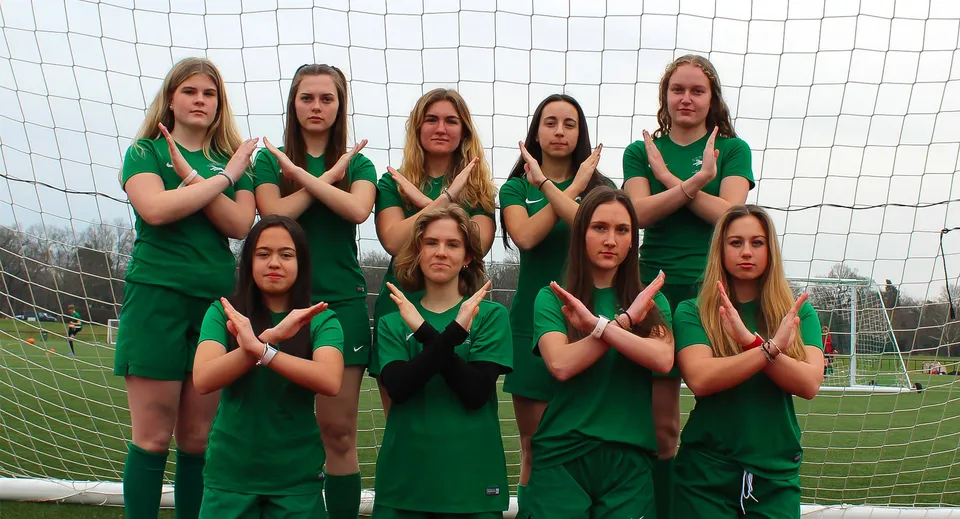Un gruppo di studentesse in divisa verde davanti alla porta da calcio sul campo sportivo della ACS International School Cobham.