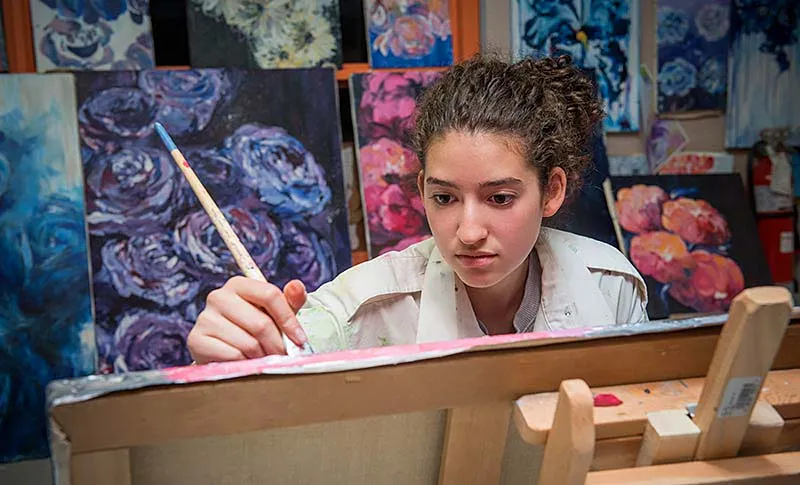 Una estudiante pinta sobre un lienzo en la clase de arte de Rockridge Secondary School.