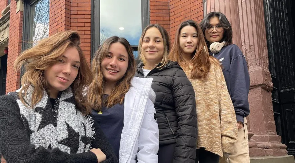 Un gruppo di giovani donne chiacchiera davanti a un edificio in mattoni all'interno del campus della The Newman School.