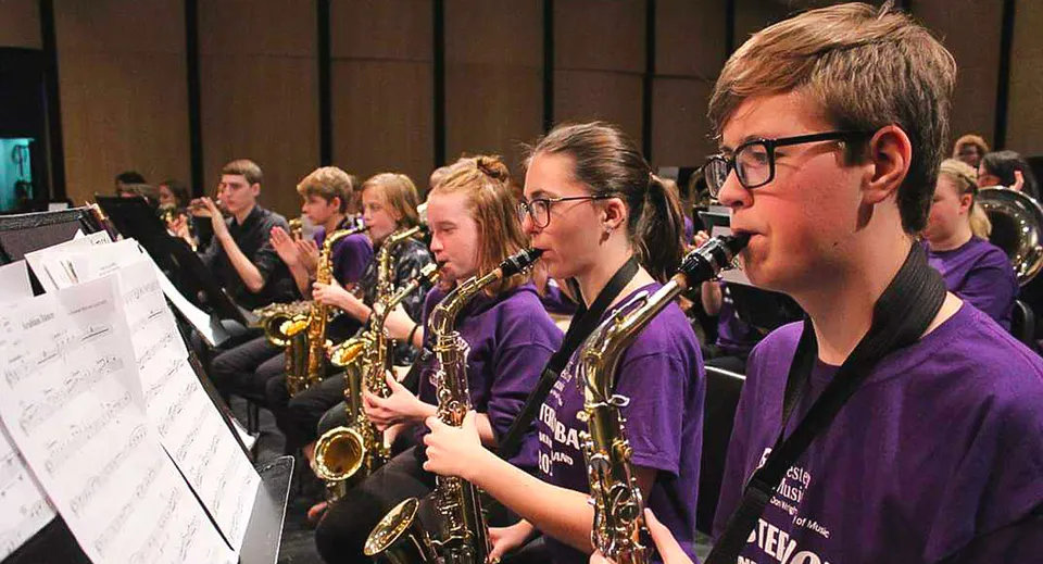 Un gruppo di musicisti e musiciste in divisa viola suona su un palco nel campus della North Lambton Secondary School.