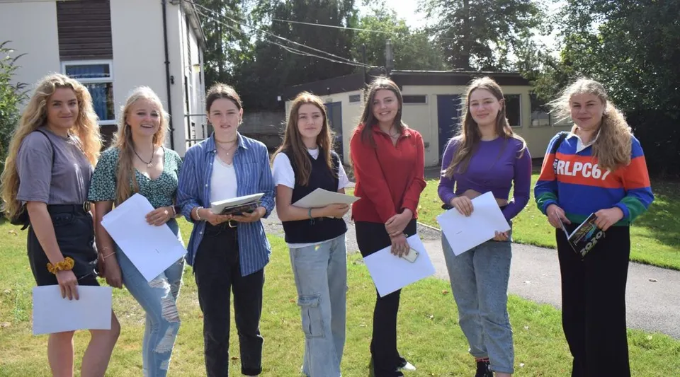 Un gruppo di studentesse della Rookwood School si trova all'aperto davanti a un edificio e tiene dei fogli in mano.