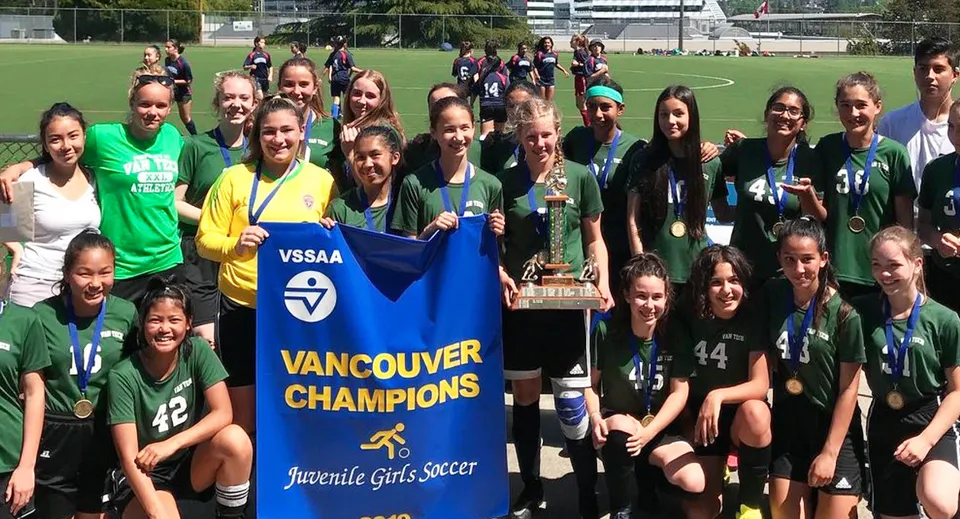 Un gruppo di giovani calciatrici della Vancouver Technical Secondary School tiene una coppa e uno striscione da campionesse giovanili sul campo da gioco.