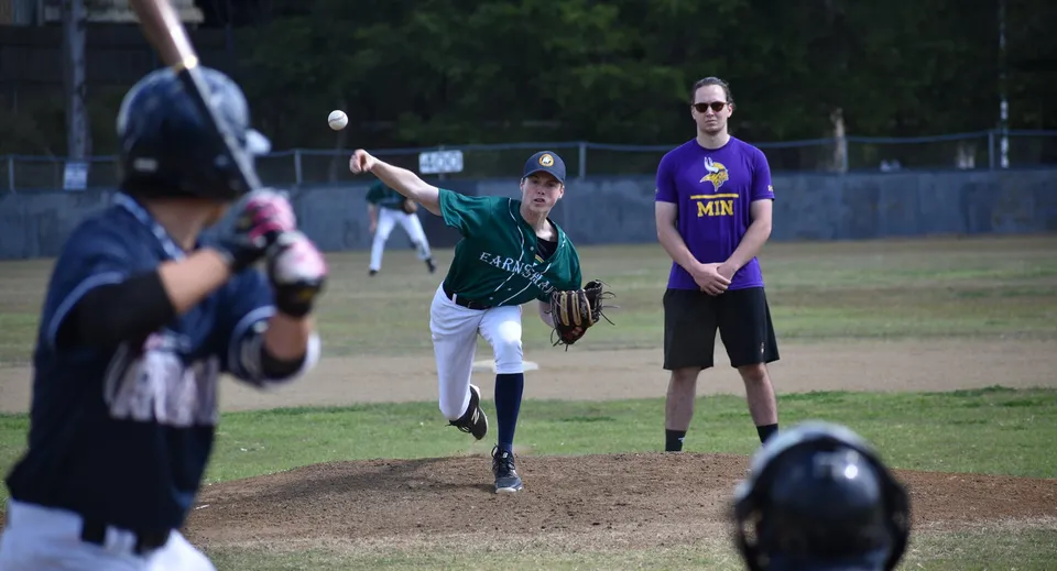 Una partita di baseball in corso sul campo sportivo dell'Earnshaw State College con lanciatore, battitore e un allenatore durante il gioco.