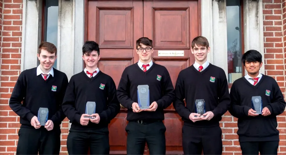 Un gruppo di cinque studenti in divisa scolastica si trova davanti a una porta in legno rossa nel terreno dell'Oatlands College.