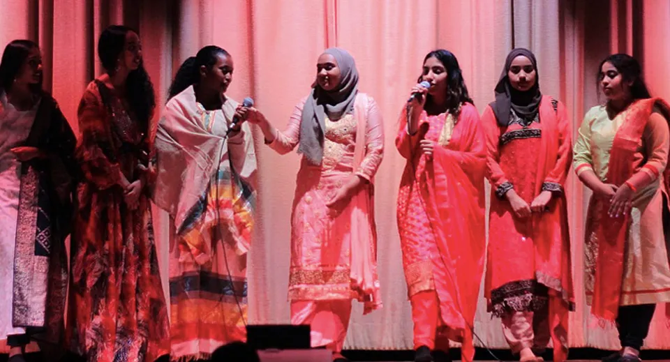 Un gruppo di studentesse in abiti tradizionali colorati si trova sul palco del Jarvis Collegiate Institute.